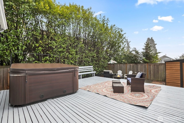 wooden terrace featuring an outdoor fire pit, fence, and a hot tub