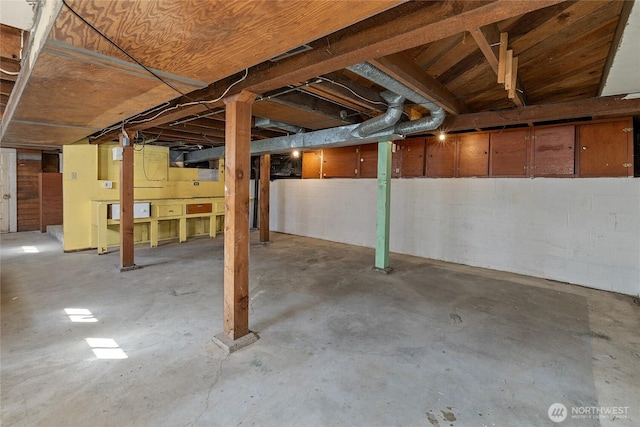 unfinished basement featuring concrete block wall