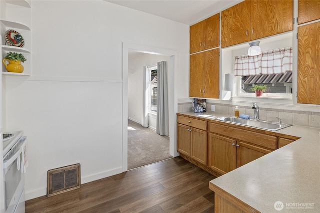 kitchen featuring dark wood-style flooring, a sink, visible vents, light countertops, and white range with electric stovetop