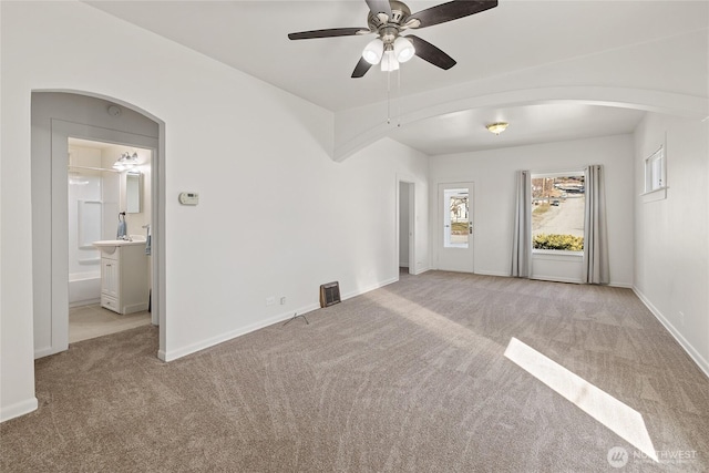 interior space featuring arched walkways, carpet flooring, baseboards, and ensuite bathroom