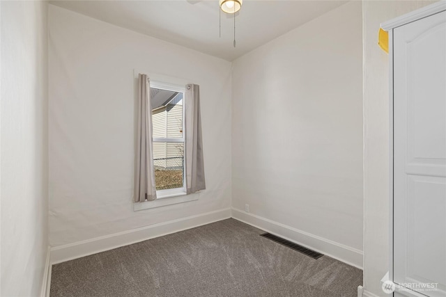 unfurnished room featuring dark colored carpet, visible vents, and baseboards