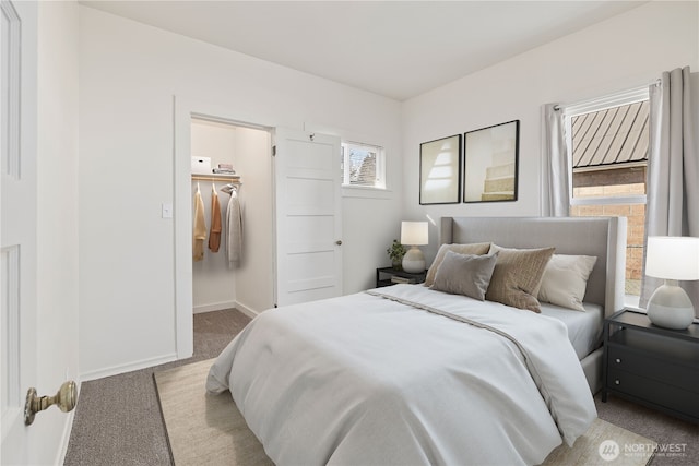 carpeted bedroom featuring a walk in closet and baseboards