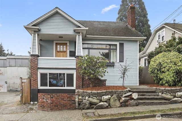 view of front of property featuring a shingled roof, a chimney, fence, and brick siding