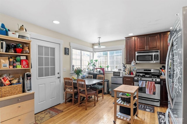 kitchen featuring light countertops, appliances with stainless steel finishes, light wood-type flooring, and dark brown cabinets