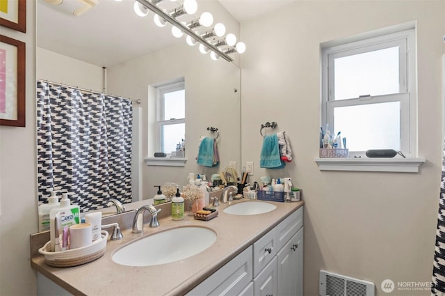 bathroom with a shower with curtain, visible vents, a sink, and double vanity