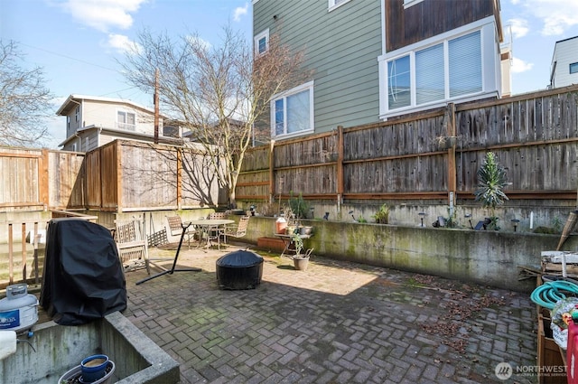 view of patio featuring a fire pit, a fenced backyard, and a grill