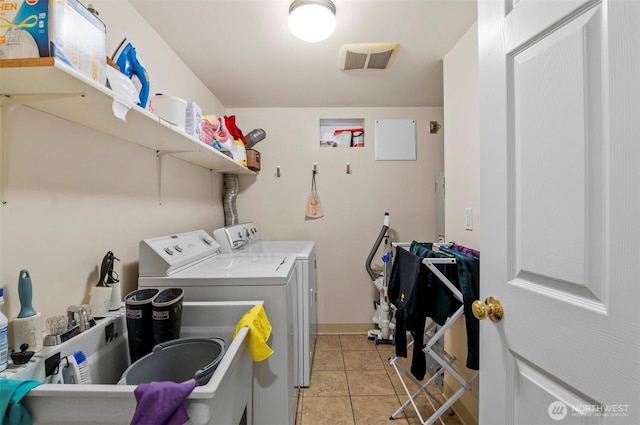 laundry area with laundry area, light tile patterned flooring, washing machine and clothes dryer, and visible vents