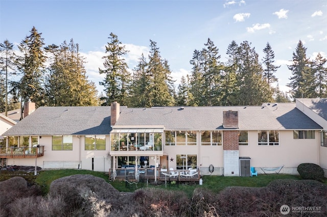 back of house featuring a chimney and stucco siding