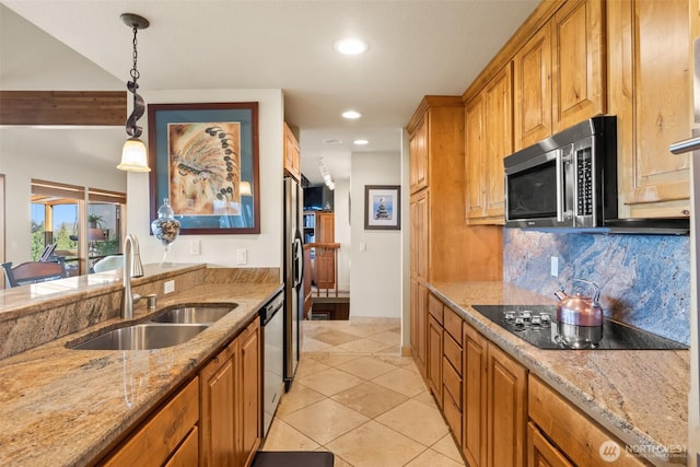 kitchen with brown cabinetry, hanging light fixtures, a sink, stainless steel appliances, and backsplash