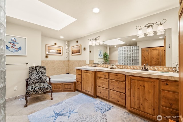 full bathroom featuring a bath, a skylight, and a sink