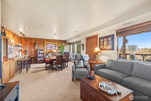 living area with carpet floors, wooden walls, and visible vents