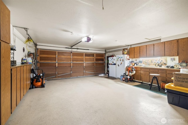 garage with a workshop area, freestanding refrigerator, and a garage door opener