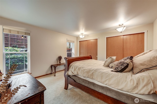 bedroom featuring light carpet, baseboards, and multiple closets