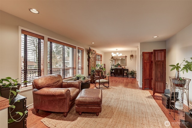 living area featuring a chandelier, recessed lighting, baseboards, and wood finished floors