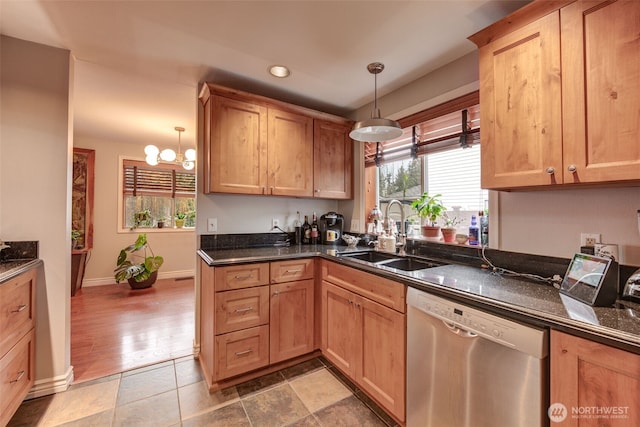 kitchen featuring baseboards, an inviting chandelier, stainless steel dishwasher, pendant lighting, and a sink