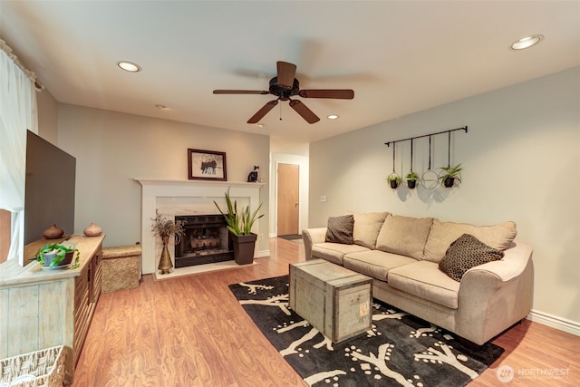 living room featuring a fireplace, recessed lighting, ceiling fan, wood finished floors, and baseboards