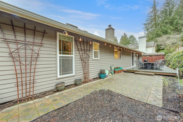 rear view of house featuring a patio area, a chimney, fence, and a wooden deck