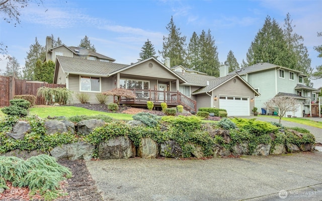 view of front of house with an attached garage, a porch, fence, and aphalt driveway