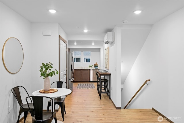 dining area featuring a wall mounted air conditioner, light wood-style floors, recessed lighting, and baseboards