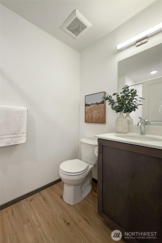bathroom with wood finished floors, toilet, vanity, and baseboards