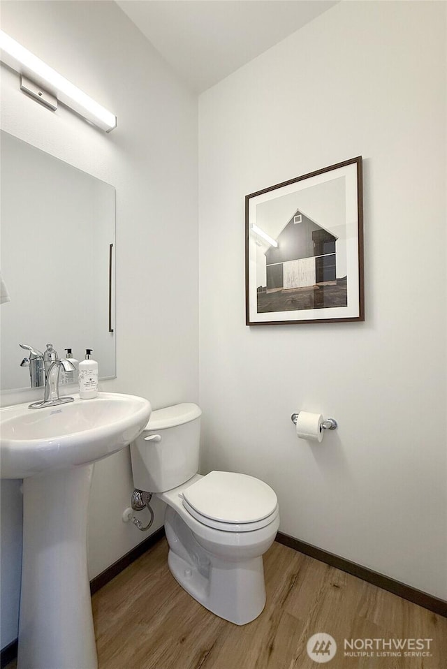 bathroom with wood finished floors, baseboards, toilet, and a sink