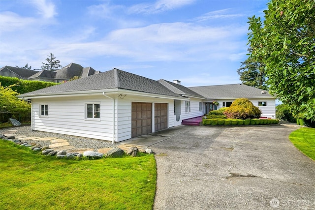 ranch-style home featuring a chimney, a shingled roof, concrete driveway, an attached garage, and a front yard