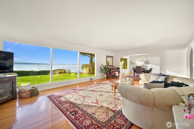living room featuring arched walkways, wood finished floors, and visible vents