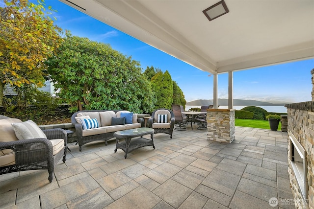 view of patio with outdoor dining space, a mountain view, and an outdoor living space with a fireplace