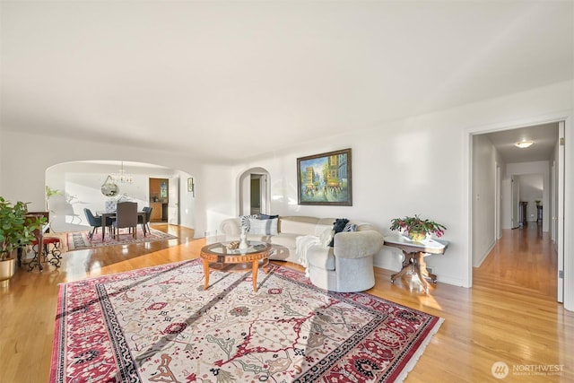 living room with a chandelier, arched walkways, and wood finished floors