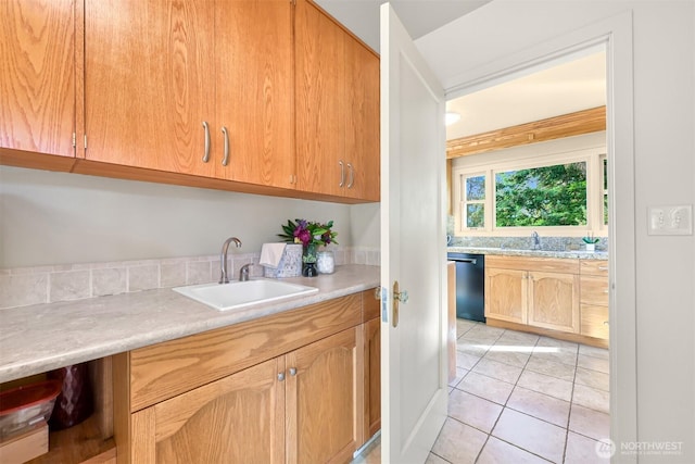 kitchen with black dishwasher, light countertops, light tile patterned flooring, and a sink