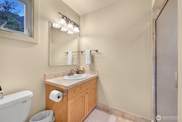 bathroom with tile patterned flooring, baseboards, vanity, and toilet