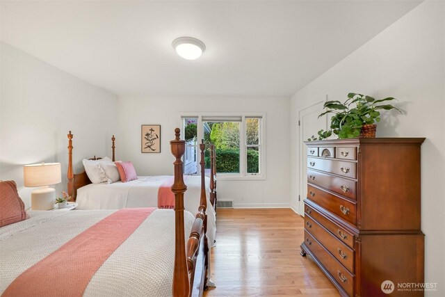 bedroom featuring light wood finished floors, visible vents, and baseboards