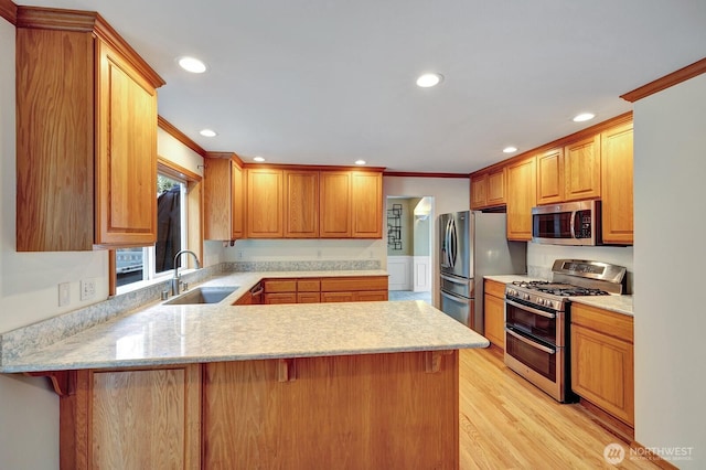 kitchen featuring a sink, appliances with stainless steel finishes, a peninsula, and crown molding