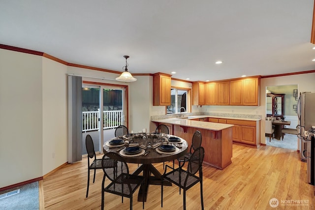 dining area featuring crown molding, baseboards, visible vents, and light wood finished floors