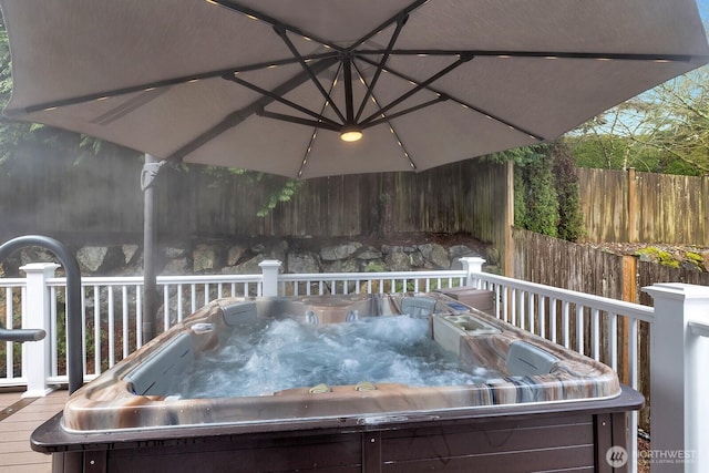 wooden terrace featuring a hot tub and fence