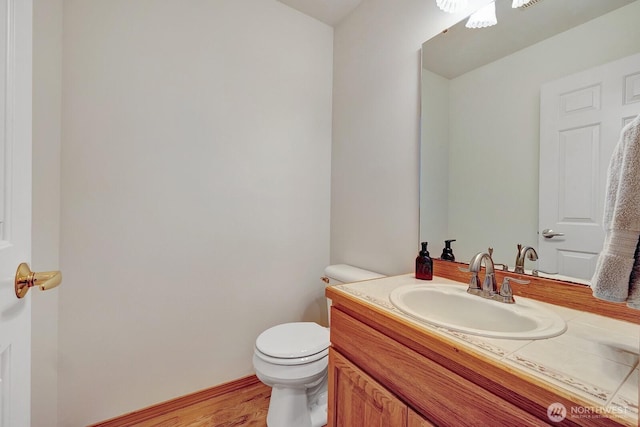 bathroom with toilet, wood finished floors, and vanity