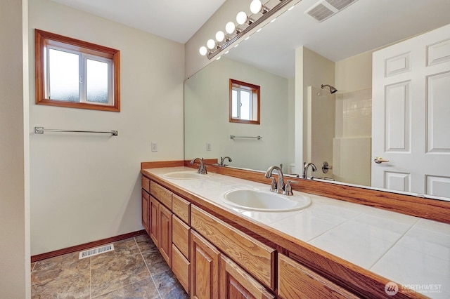 full bathroom with visible vents, tiled shower, and a sink