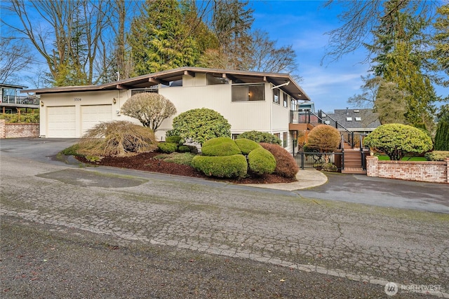 view of front facade with driveway, an attached garage, and stairs