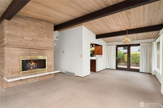 unfurnished living room featuring visible vents, lofted ceiling with beams, wooden ceiling, a stone fireplace, and carpet floors