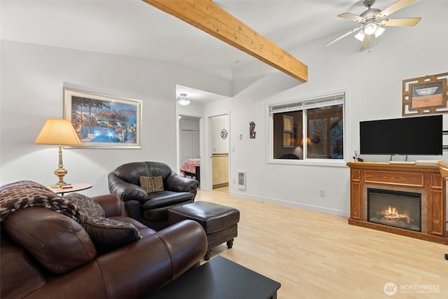 living area featuring visible vents, baseboards, a glass covered fireplace, wood finished floors, and beam ceiling