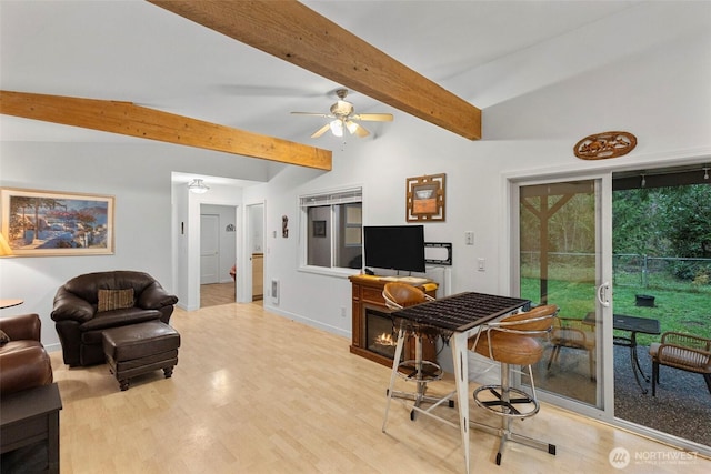 living room with a ceiling fan, baseboards, lofted ceiling with beams, and light wood finished floors