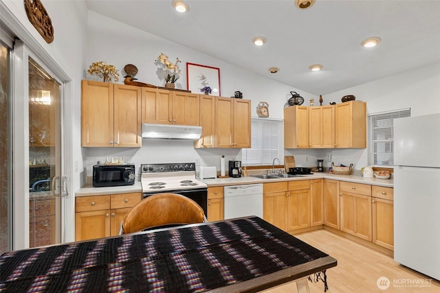 kitchen featuring white appliances, under cabinet range hood, and light brown cabinetry