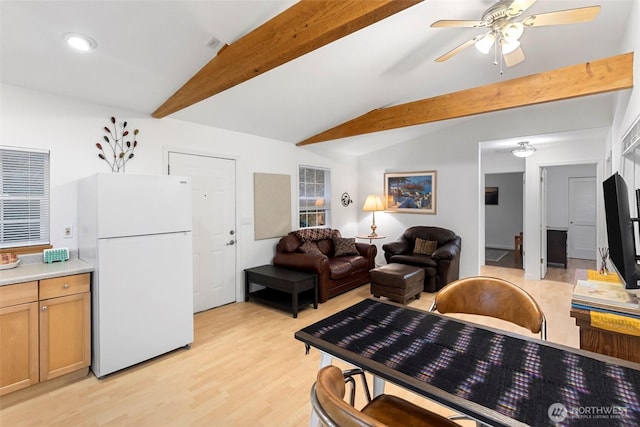 living area with vaulted ceiling with beams, light wood-type flooring, and a ceiling fan