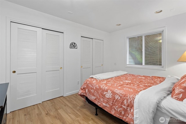 bedroom with baseboards, recessed lighting, wood finished floors, and multiple closets