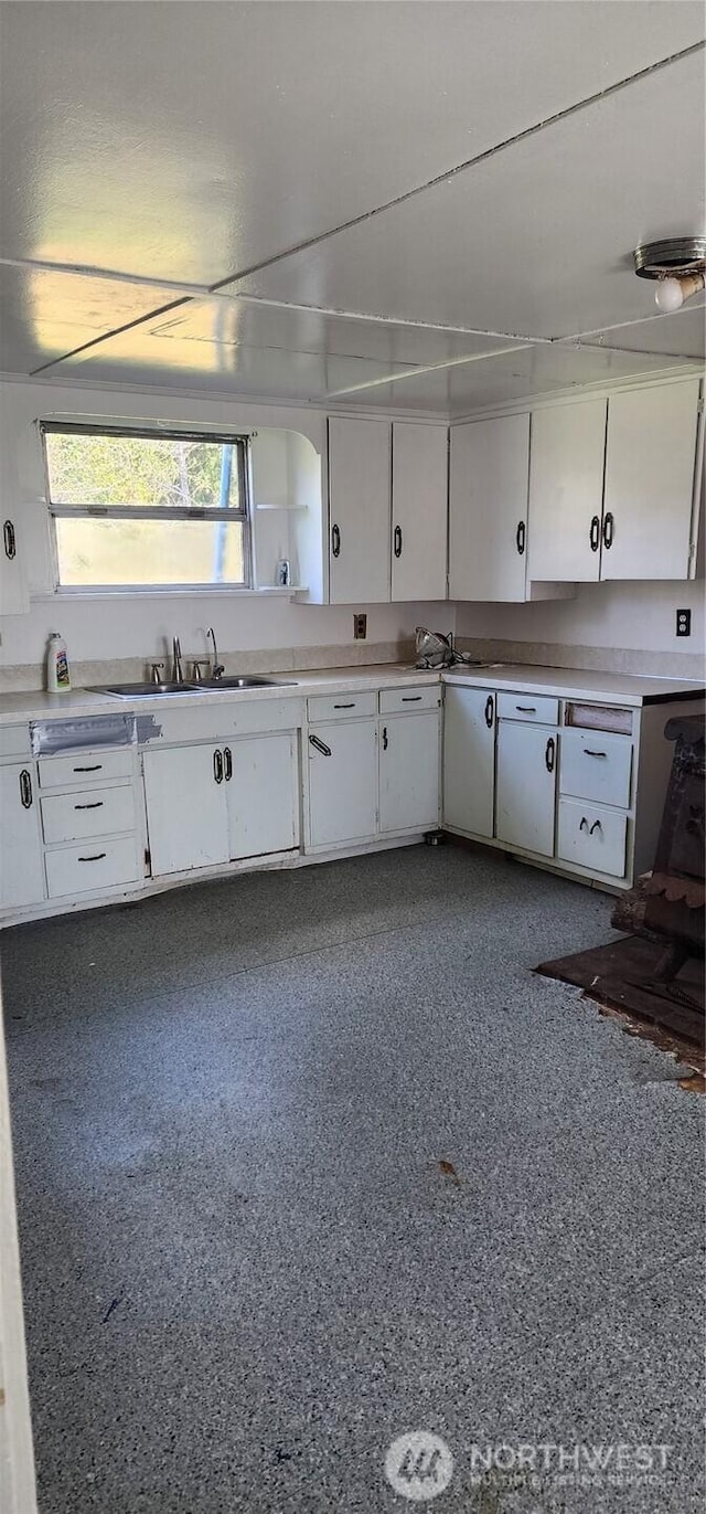 kitchen featuring light countertops, a sink, and white cabinetry