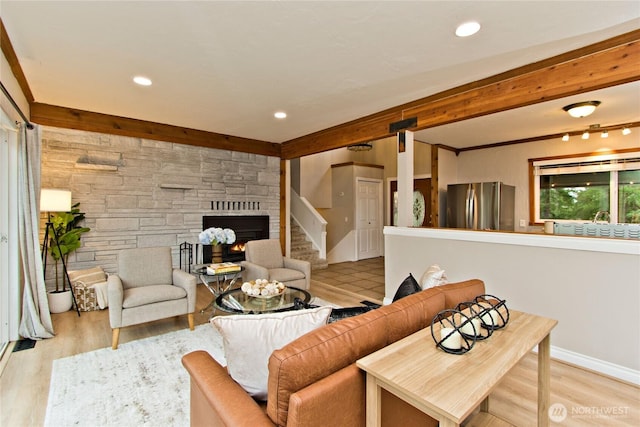 living area featuring light wood-style flooring, recessed lighting, beamed ceiling, and a stone fireplace