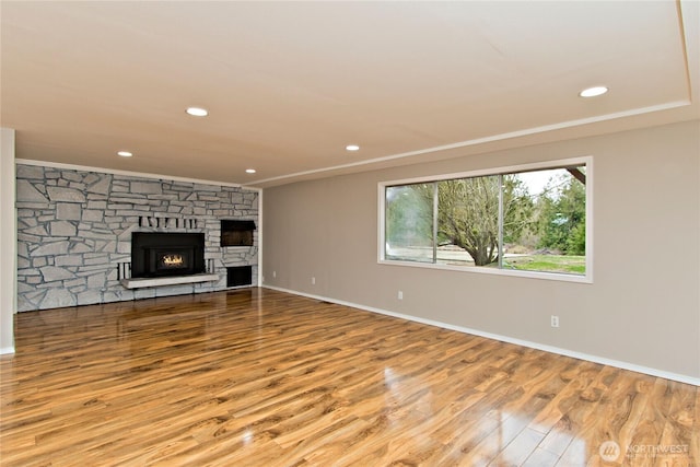 unfurnished living room with recessed lighting, wood finished floors, and a stone fireplace