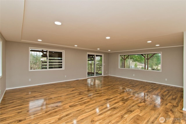 spare room featuring baseboards, crown molding, wood finished floors, and recessed lighting