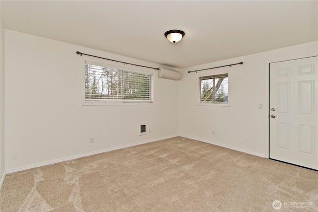 spare room featuring an AC wall unit, light colored carpet, and baseboards