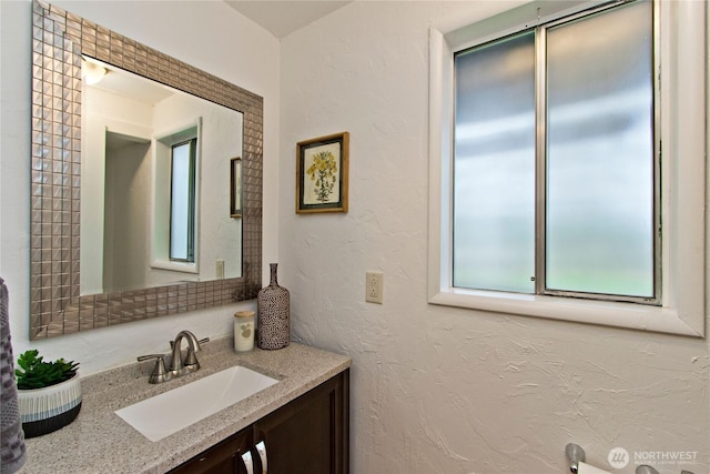 bathroom featuring vanity and a textured wall